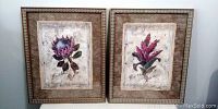 Two framed floral prints side by side on a wall, showing full view of artwork and frames
