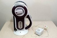 Black and Decker Dustbuster handheld vacuum cleaner with white charging base and power adapter plug on a flat surface, front-side view.