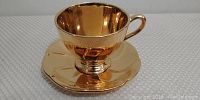 Golden Age gold reflective saucer matching the cup, showing smooth surface and color.