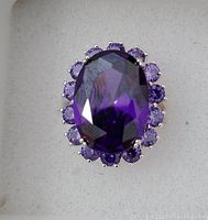 Top view of sterling silver ring with large oval amethyst center stone surrounded by smaller round amethysts