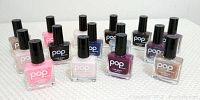 15 bottles of Pop Beauty nail glam nail polish in assorted colors arranged on a white surface.