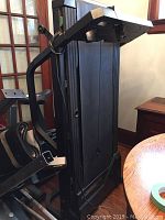 Folded treadmill showing side structure and part of control panel area.