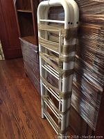 Side view of bundled white tubular metal uprights and rack shelves in a stacked position with tan tape holding them together.