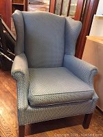 Front view of solid wingback chair with blue patterned upholstery showing overall condition.