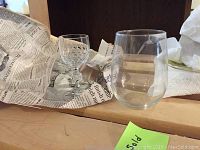 Cut glass crystal stemware and clear stemless tumbler glass, wrapped in newspaper