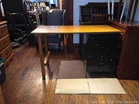 Full view of the custom desk setup showing plywood top resting on a vintage metal file cabinet and wooden legs.