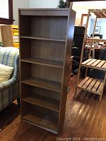 Full front view of tall bookcase with five shelves, showing dark wood veneer finish and overall structure.