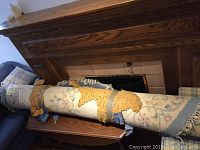 Wool oval rug rolled up, showing cream and floral pattern with blue border; placed on furniture for display