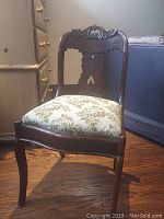 Front view of side chair with carved wood back and floral upholstered seat