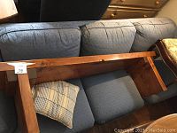Bench shown upside down on blue sofa, showing thick legs and the wood grain.