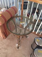 Full view of round end table showing clear removable glass top and metal base with decorative detail