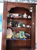 Wooden shelving unit containing various decorative items including vases, jars, picture frames, and figurines