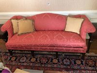 Front view of coral damask sofa with two fringe-trim pillows