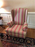 Front view of the striped wingback chair showing its upholstery and shape.