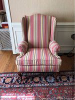 Front view of the striped wingback chair showing the seat cushion, armrests, and leg details.