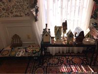 Wide view of multiple birdhouses on a shelf and tiles on a bench beneath, showing the arrangement of items in the lot.