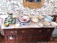 Display on wooden dresser including pie plate with lid, floral bowls and plates, lemon plate and canister, and other ceramic bowls and dishes as described in seller note.