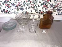 Full view of entire glass collection on table showing Waterford crystal canister, bowl, candlesticks, colored vases, and plates