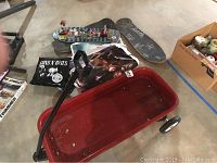 Photo of red Radio Flyer wagon, vintage rock posters, old skateboard decks, and other items on concrete floor
