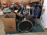 Full drum kit setup showing bass drum, toms, cymbals, stands, throne and case box