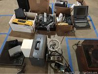 Wide shot showing all items in lot including boxed old phones, portable radios, word processor, projector, and camera.