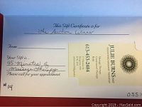 Photo of a gift certificate for a 45 minute massage therapy session with handwritten details specifying "The Auction Winner" and "45 Minutes of Massage Therapy" along with a business card for Julie Burns RMT providing contact information.