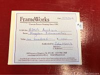 Photo of $100 gift certificate from Kingston FrameWorks, showing printed details including value, authorization, and date.