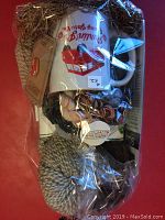 Clear wrapped gift bag with a white ceramic mug featuring red and black Purlin Js Roving Yarn Co. logo, assorted yarn skeins, wooden knitting needles, and a pin visible through the plastic.