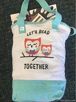 Canvas tote bag with owl reading design containing visible books inside