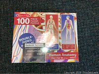 Photo of Melissa & Doug 100-piece double-sided floor puzzle box showing human anatomy graphics and branding.