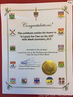 White certificate with decorative green border, crest logos and gold seal, stating lunch for two at Parliamentary Restaurant and tour of West Block