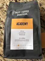 Photo of matte black 340g bag of Pilot Coffee Roasters Academy coffee with flavor notes and branding.