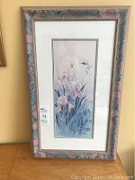 Full view of the framed artwork showing floral frame and vertical rectangular print of flowers and hummingbird.