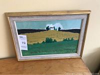 Full view of framed oil painting depicting a hill with a house under a blue sky.