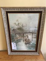 Full view of framed Japanese watercolour painting with a man in a boat under a bridge.