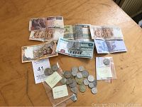 Initial overview photo showing a mix of foreign banknotes and coins spread on a wooden surface.