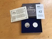 Set of two commemorative coins in box with information card and auction lot card.