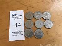 Eight Canadian silver dollar coins on wooden surface arranged in rows. Coins show various dates and similar silver finish.