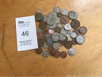 Photo showing a variety of old English coins spread on a wood surface with different sizes and metal tones including silver and copper.