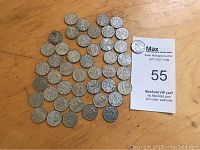 54 George VI Canadian nickels laid out on a wooden surface, front side visible with profile of King George VI on most coins.