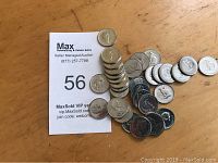 Over 30 Canadian nickel coins from 1967 displayed on a surface with a MaxSold auction card visible.