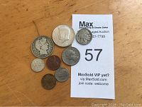 Photo of the small lot of 8 American coins including the Indian Head nickel, Barber quarter, Kennedy half dollar, Mercury dime, and Lincoln cent arranged on wooden surface beside auction lot card.