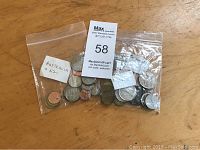 Two sealed plastic bags filled with assorted coins from Australia and New Zealand, identified by handwritten label inside the bag.