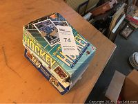 Box of 1990 hockey cards with unopened bubble gum packs on a wooden surface.