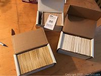Three open white cardboard boxes filled with hundreds of baseball cards stacked vertically, showing worn but intact cards.