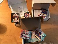 Three open cardboard boxes filled with hockey cards, some cards visible with different players and team uniforms.