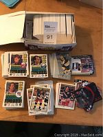 Two open boxes filled with hundreds of hockey cards shown on a wooden surface, cards are sorted into stacks and loose mixed, featuring several NHL players.