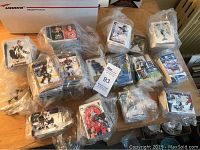 Overview of multiple plastic bags filled with hockey cards laid out on a table, showing numerous stacks with images of players in hockey gear and team colors.