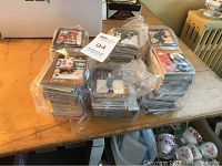 Six plastic bags filled with hundreds of hockey cards stacked and placed on a wooden table.