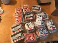 Box with 12 sealed sets of hockey cards, each wrapped in plastic bags, displayed on a wooden surface.
